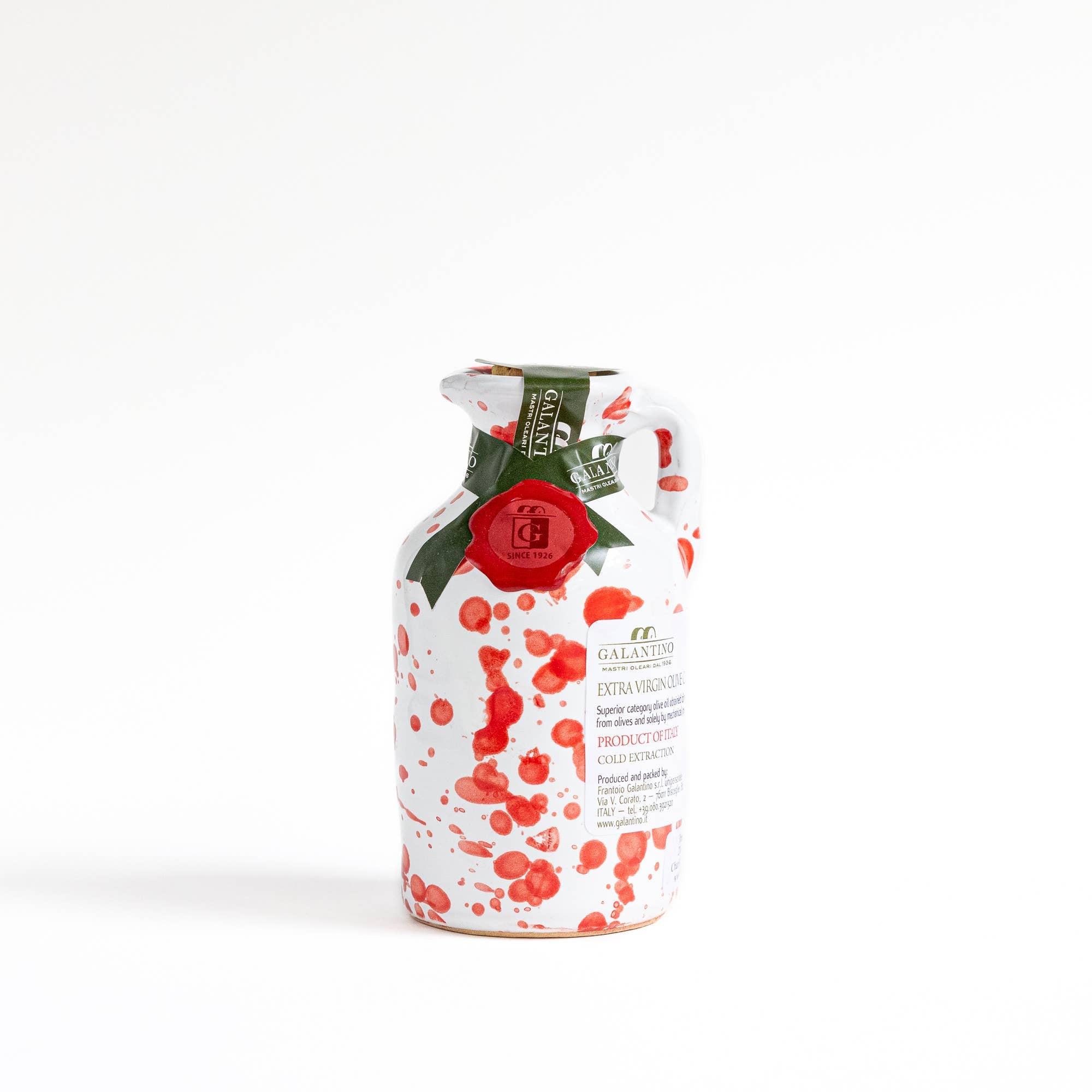 Small red splatter ceramic bottle of olive oil with cork top on white background 