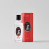 White bottle with black cap and red box featuring decorative design on a gray background