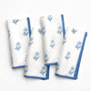 Set of four white napkins with blue floral embroidery on a white background