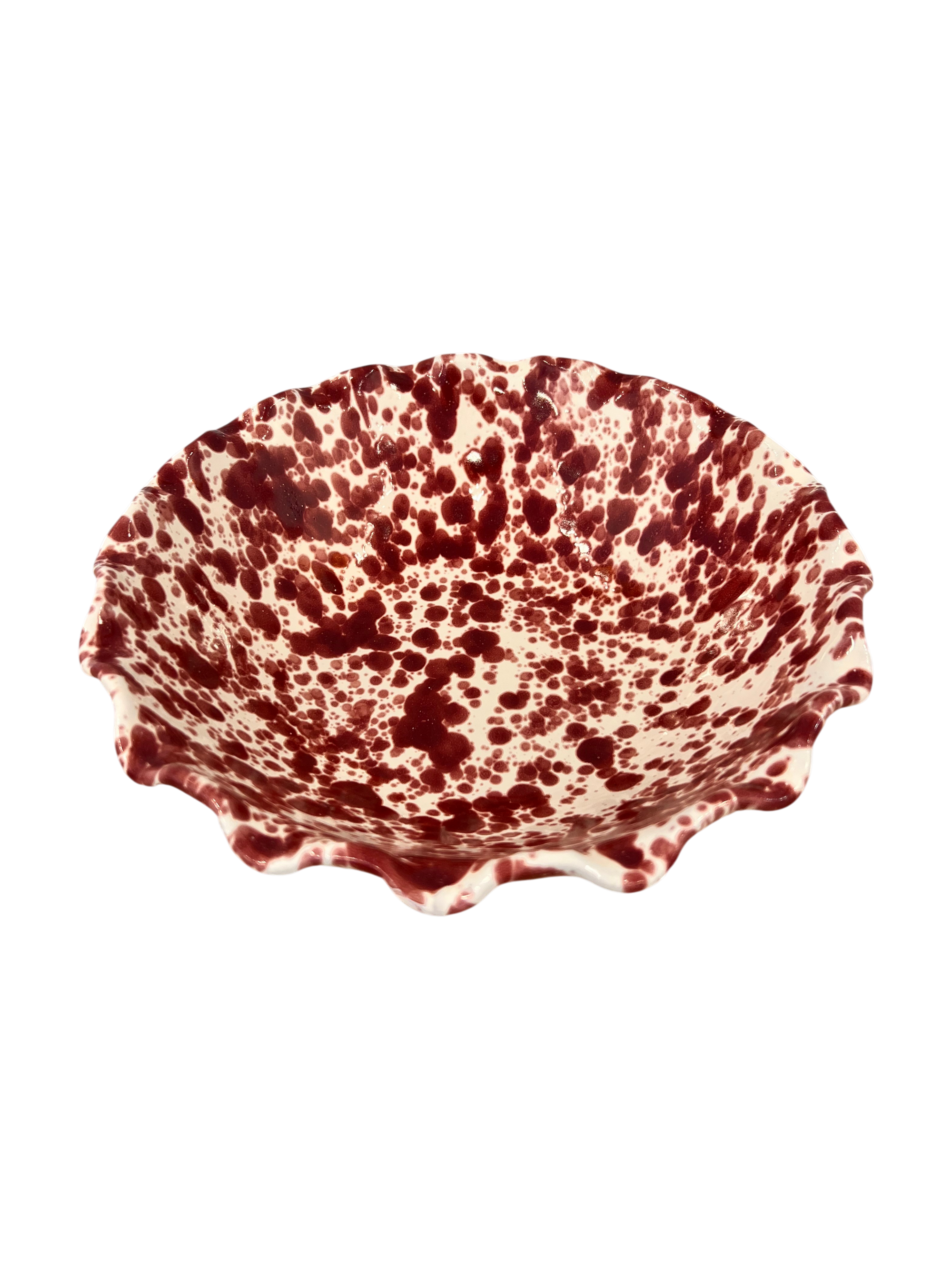 A ceramic bowl with a scalloped rim, featuring a dark red speckled pattern on a white glazed background, isolated on a white background.