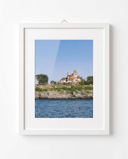 Framed photograph of a house by the water on a white wall