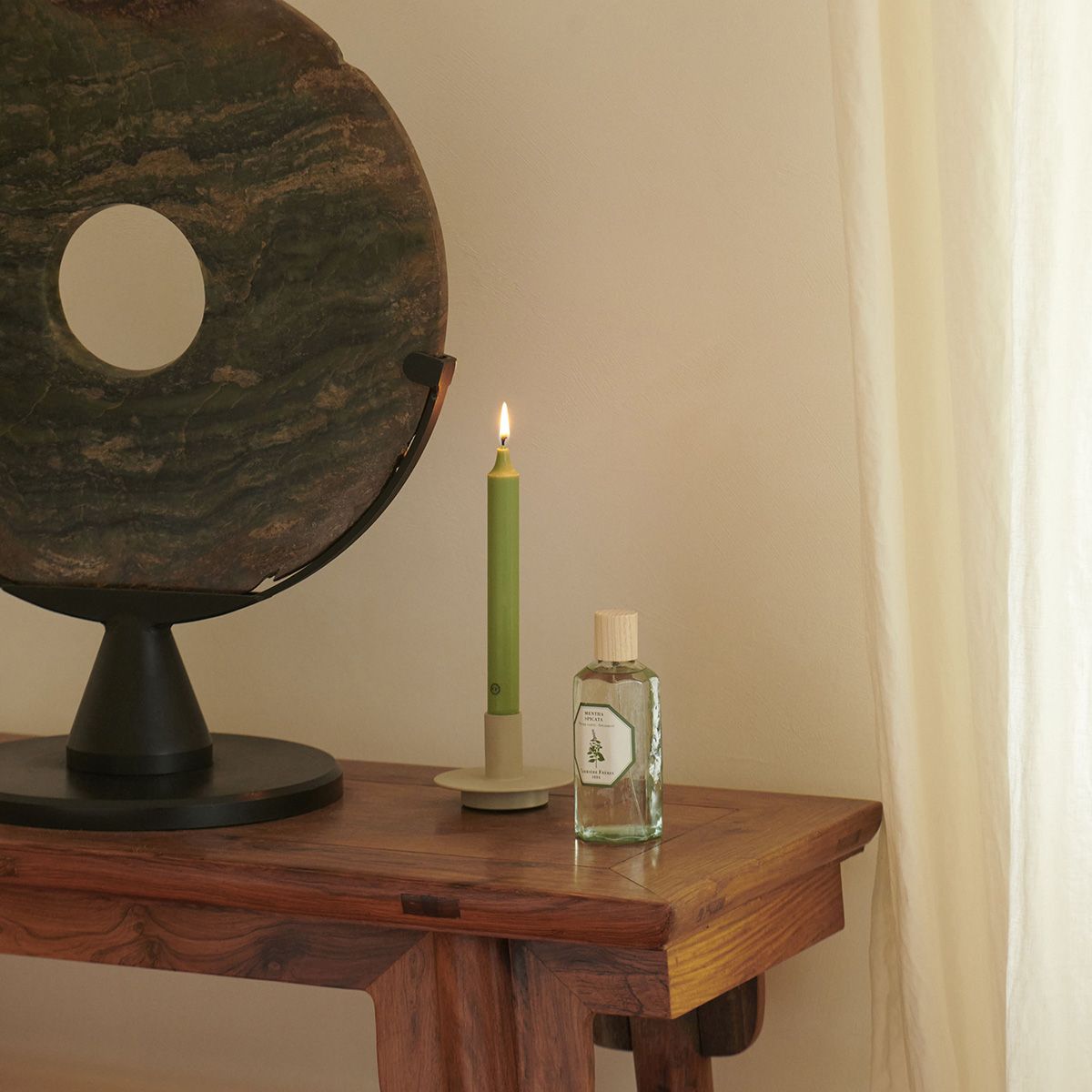 Vintage-style globe, candle, and bottle on a wooden surface with a neutral background