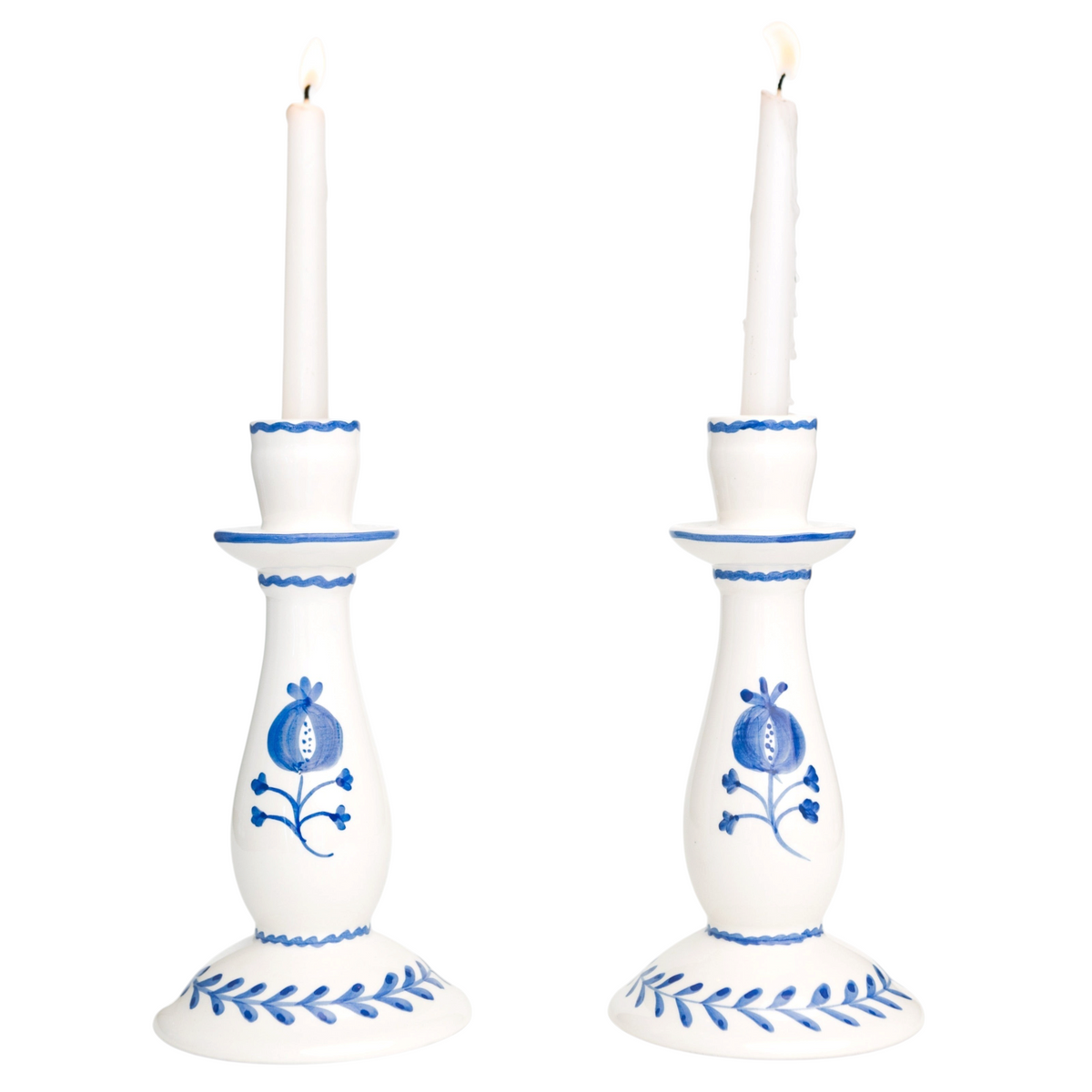 White candlesticks with blue floral patterns holding lit candles on a white background