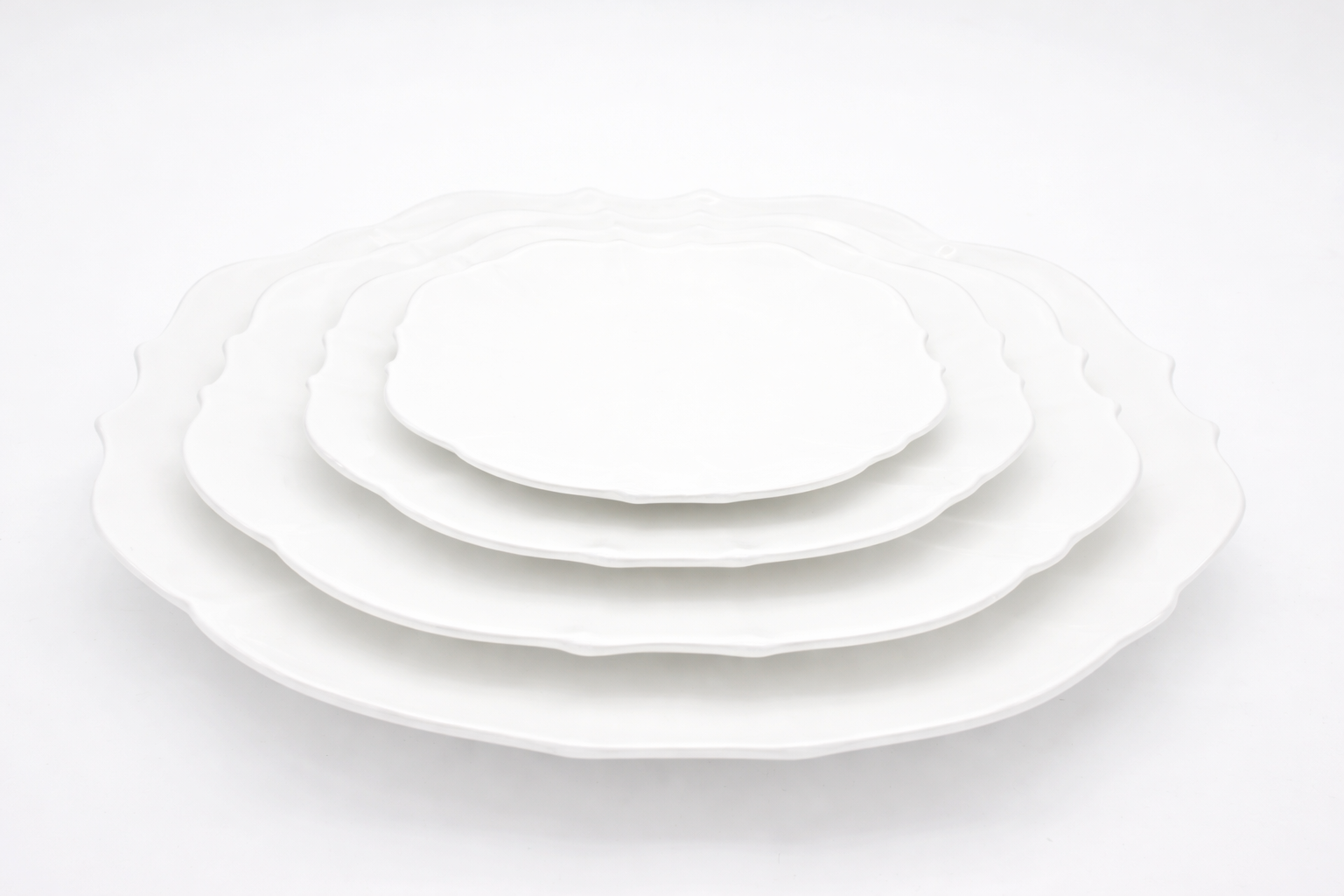 Set of white ceramic plates of different sizes on a white background