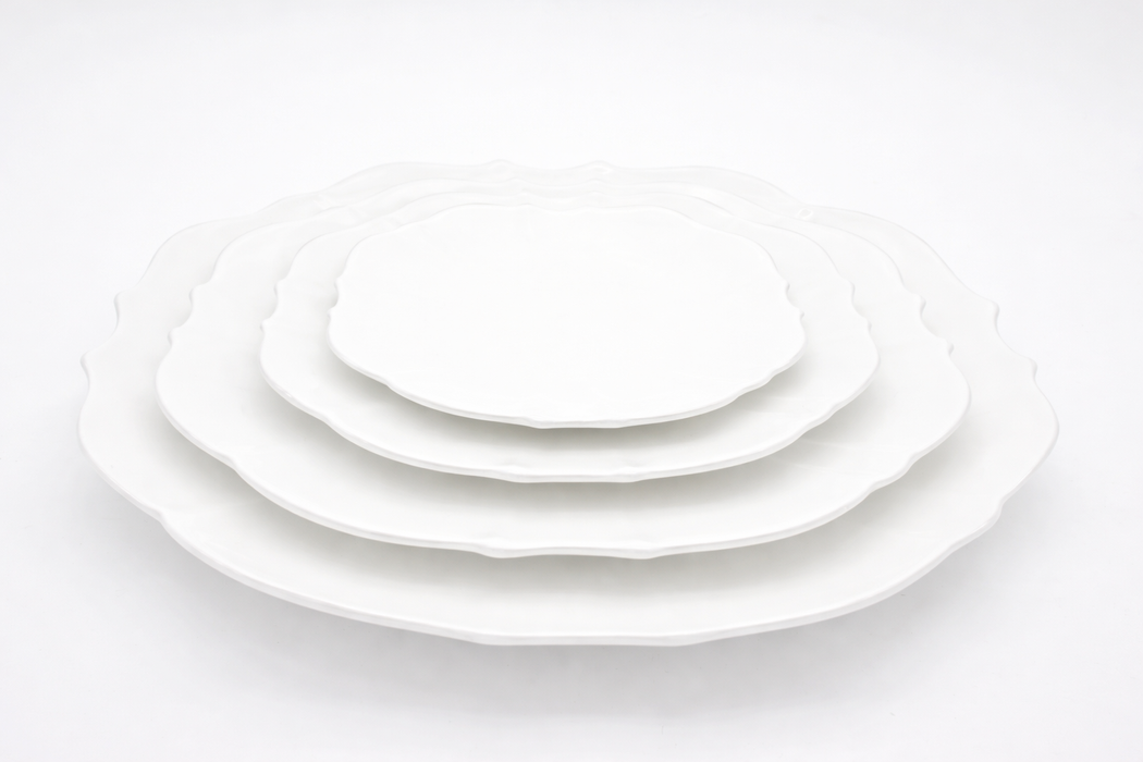 Set of white ceramic plates of different sizes on a white background