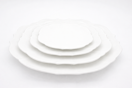Set of white ceramic plates of different sizes on a white background