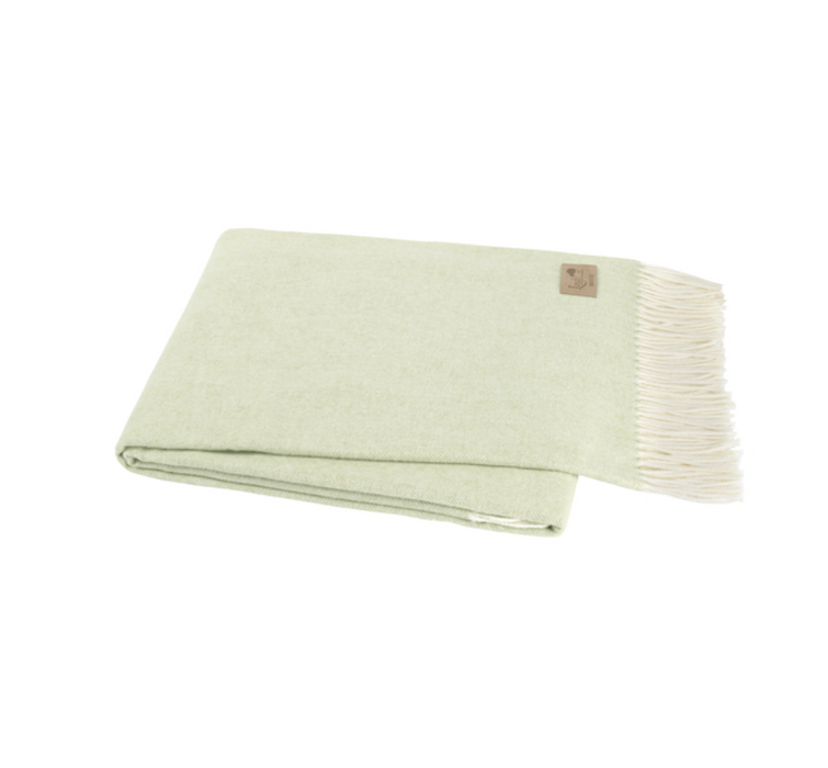 Light green blanket with white fringe on a white background