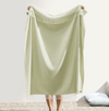 Light green blanket being held up on a white background