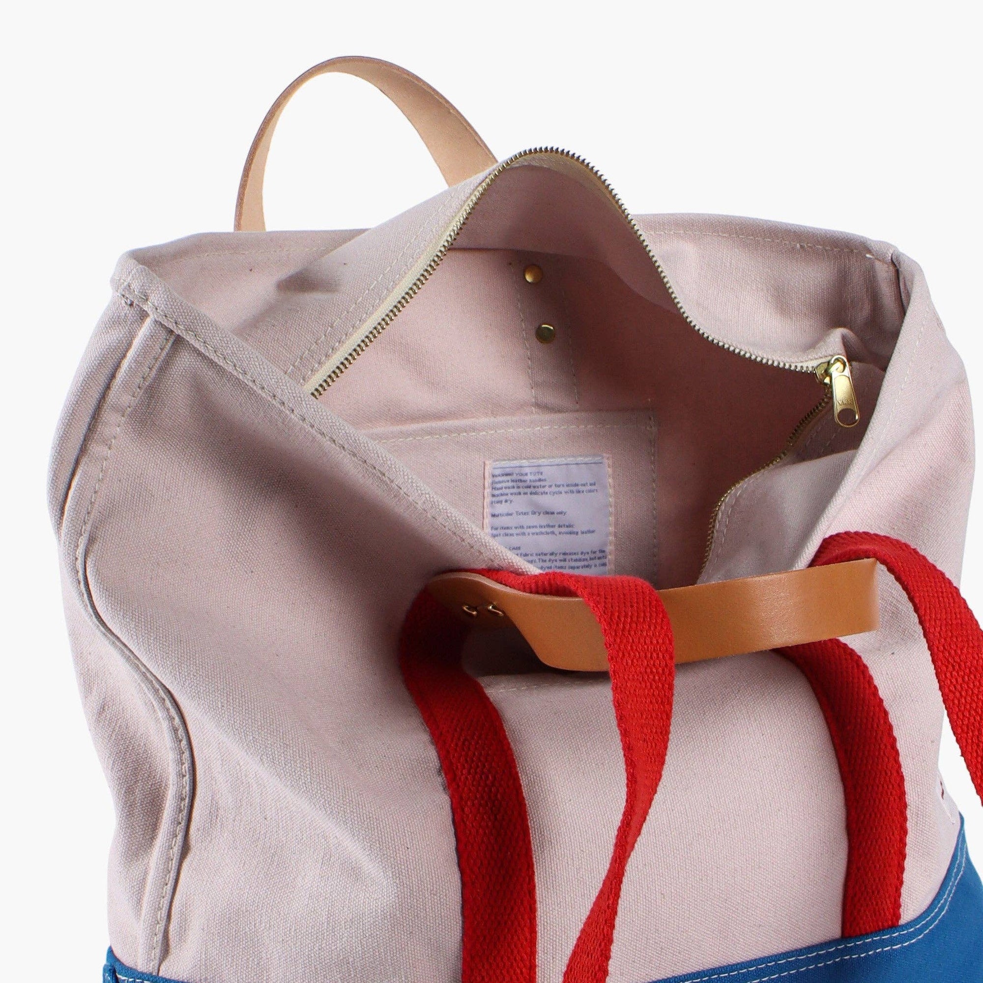 Canvas sky tote with red shoulder strap and leather handles and zipper 