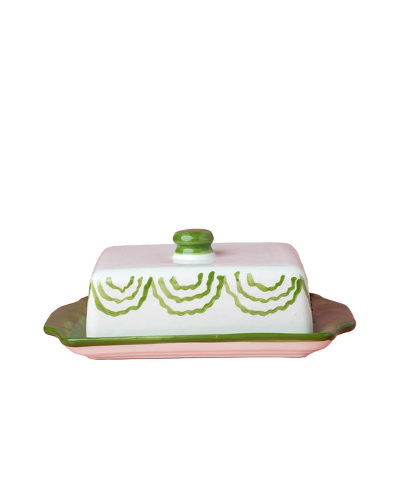 Butter dish with green lid and decorative pattern on a pink background