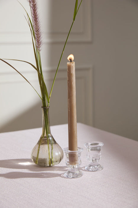 Candle in a glass holder with a vase of grasses on a neutral background
