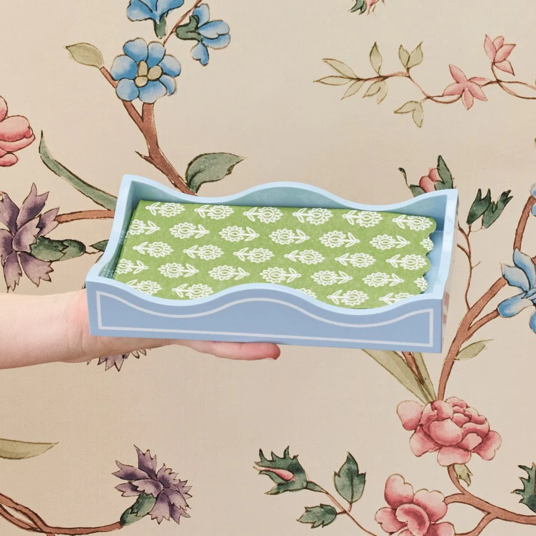 blue laquered napkin holder with green napkins and floral background