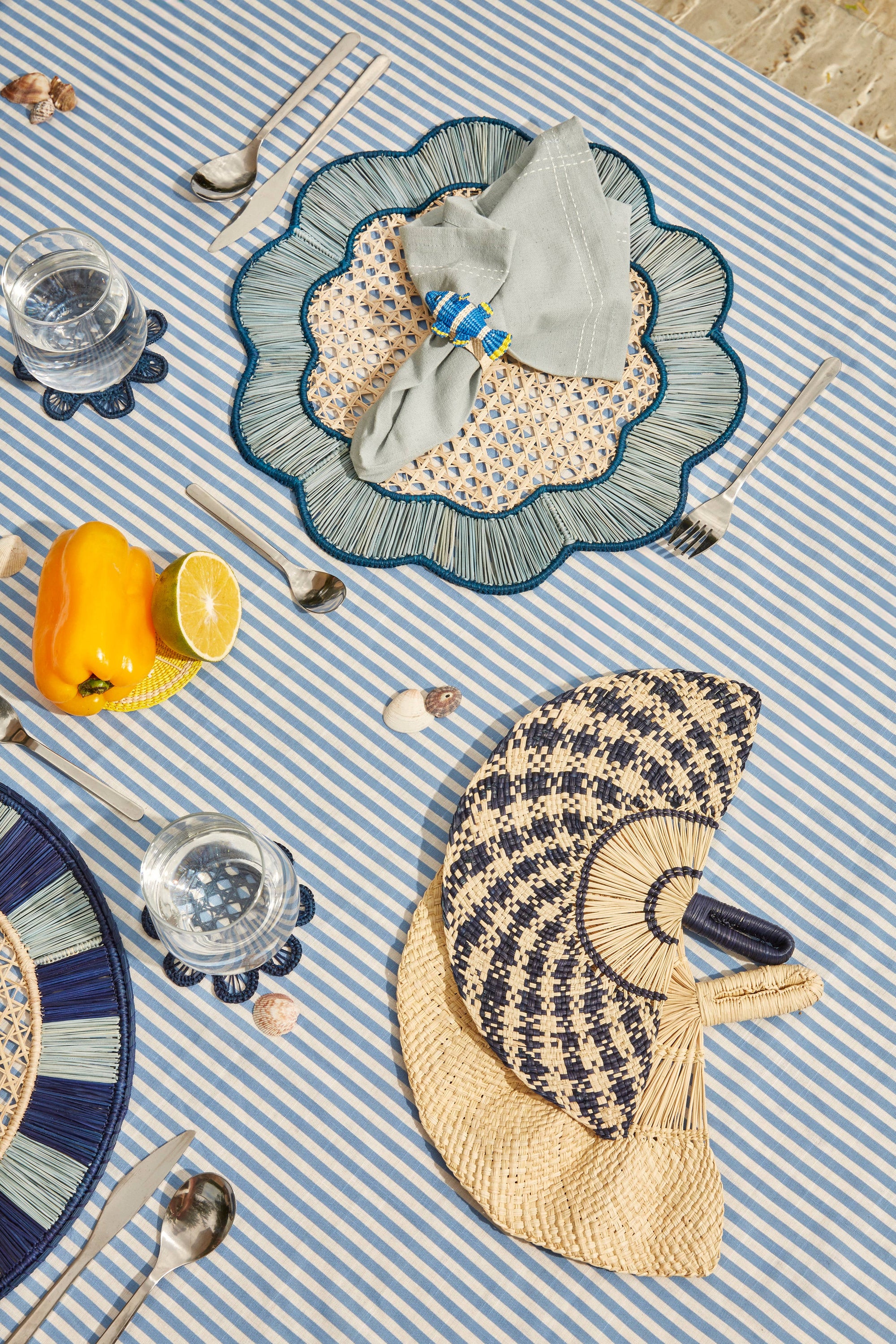 Table setting with decorative placemats, cutlery, and a striped tablecloth.