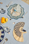 Table setting with decorative placemats, cutlery, and a striped tablecloth.