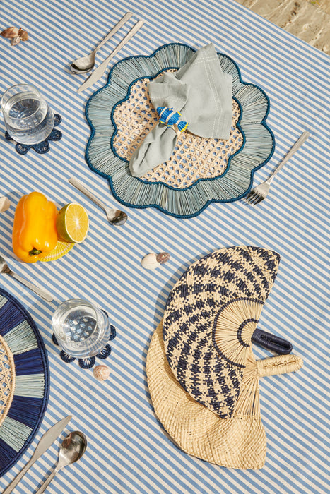 Table setting with decorative placemats, cutlery, and a striped tablecloth.