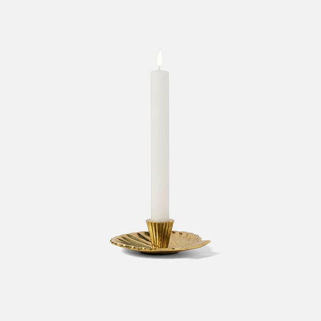 Gold candle holder with a white candle on a white background