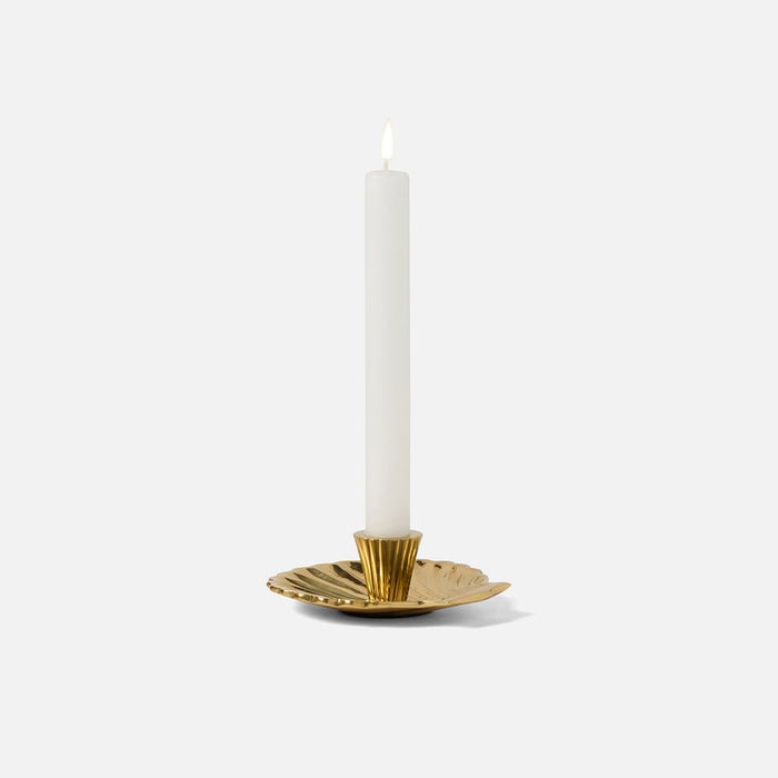 Gold candle holder with a white candle on a white background