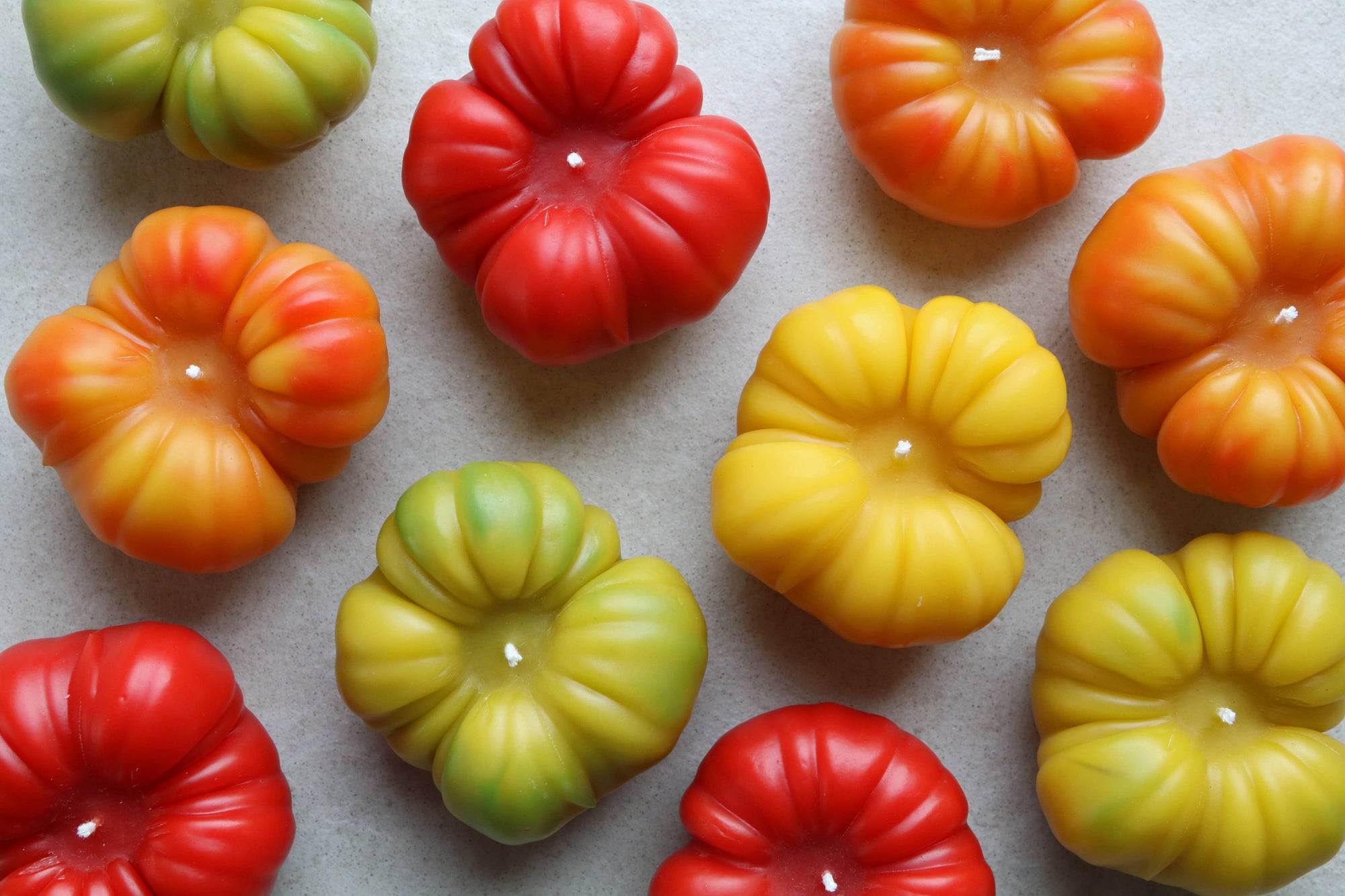 Colorful tomato-shaped candles on a neutral background