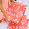 Person holding a folded pink bandana with white patterns