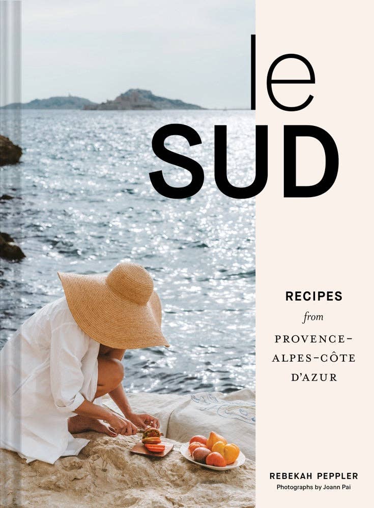Cover of le Sud cookbook with lady in a hat by the ocean cutting a tomato 