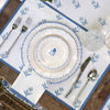Set table with blue floral patterns on a white plate, silverware, and glass on a wooden table.