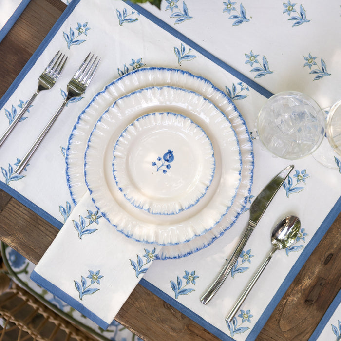 Set table with blue floral patterns on a white plate, silverware, and glass on a wooden table.