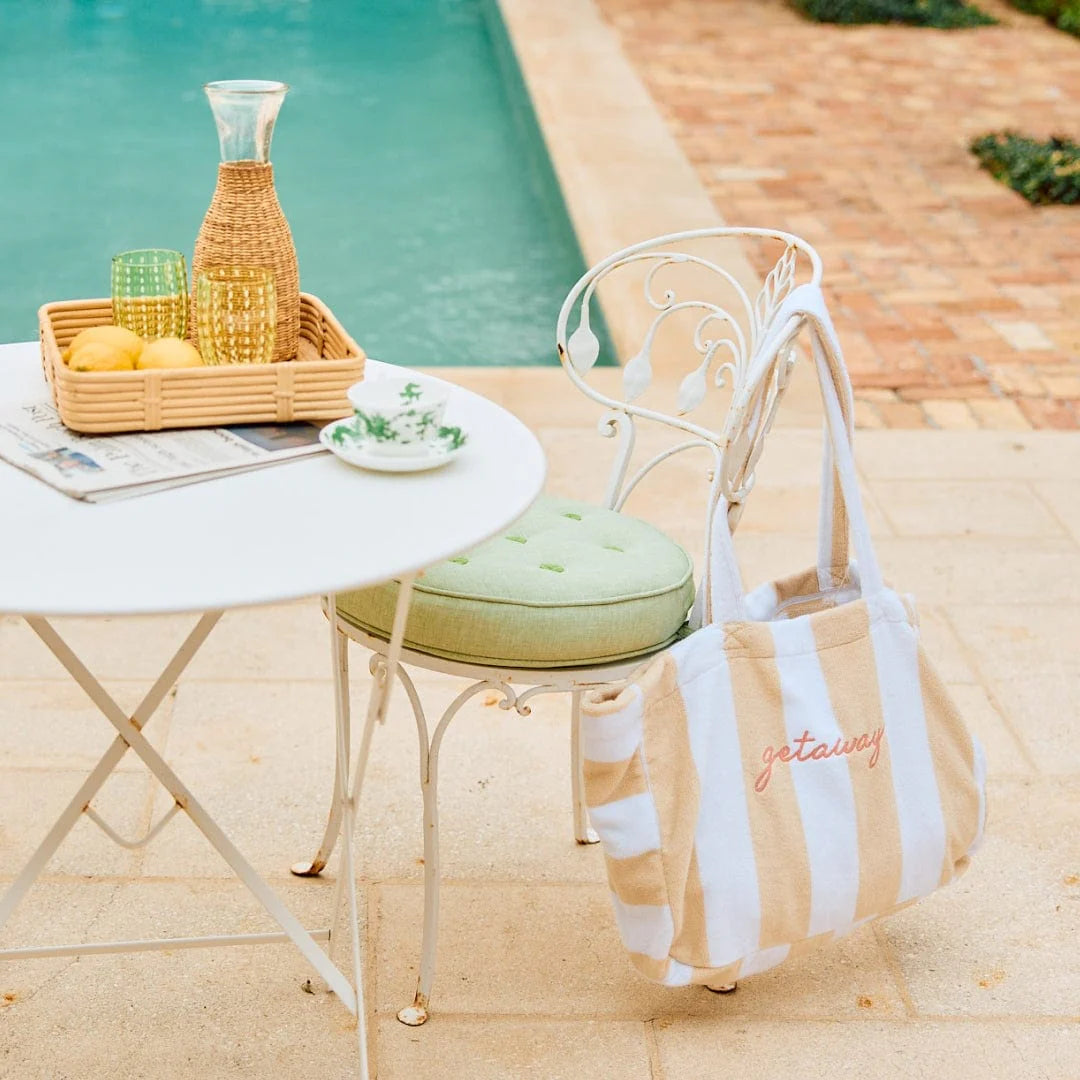 sand striped monogramed beach bag on back of chair at pool