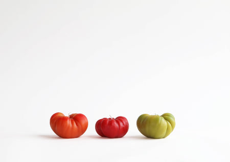 Three tomatoes of different colors (red, red, green) on a white background