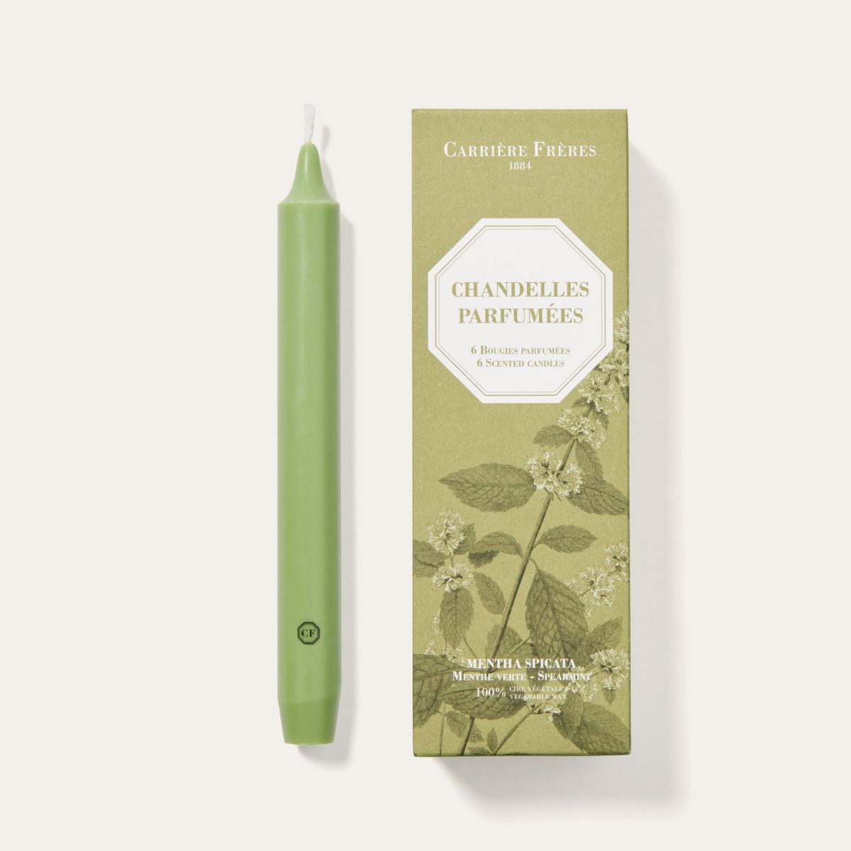 Green candle and its packaging on a white background
