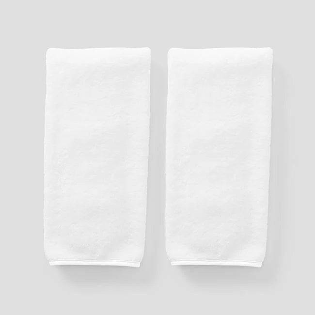 2 white on white signature towels on grey background