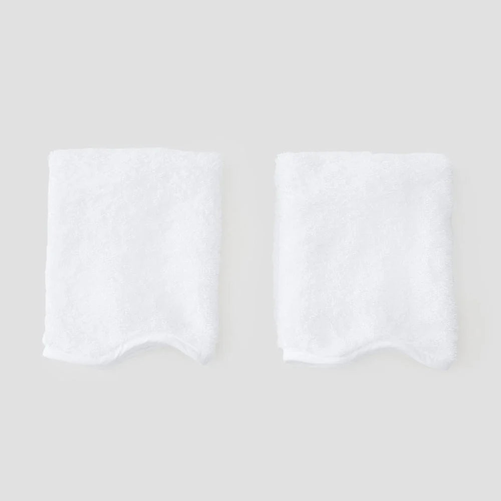 Two white on white washcloths on grey background